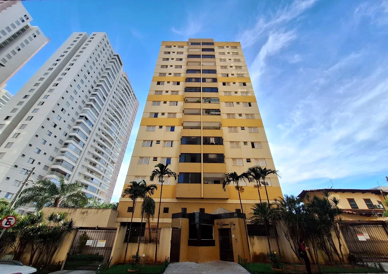 Vista ampla da Rua 55 com a torre amarela do Residencial entre prédios brancos mais altos, sob céu azul.