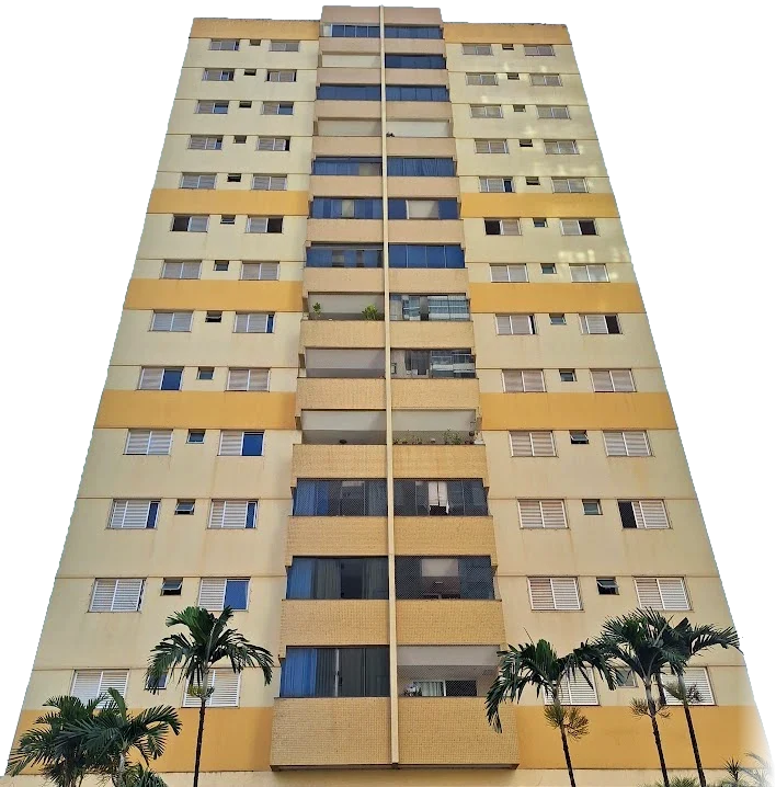 Fachada do Residencial Dr. Valdemiro Cruz vista da calçada: torre em amarelo-palha com faixas ocre, varandas no centro e palmeiras na frente.